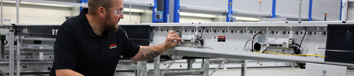 RSC technician inspecting conveyor controls in warehouse.