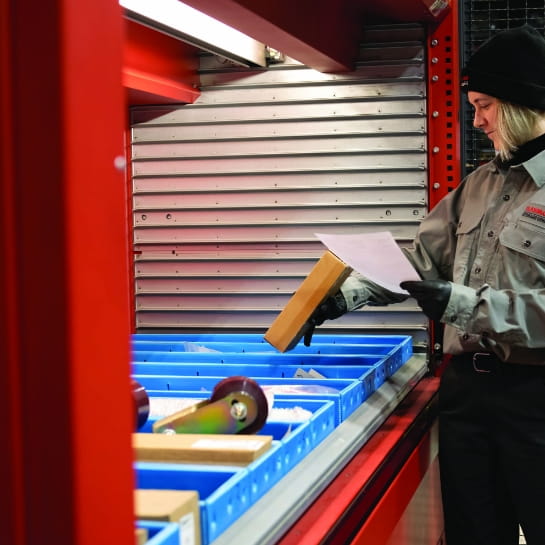 RSC parts specialist reviewing a paper order sheet while pulling inventory from an AS/RS.