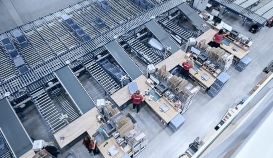 Multi-line conveyor system feeding warehouse packing stations for efficient order fulfillment.