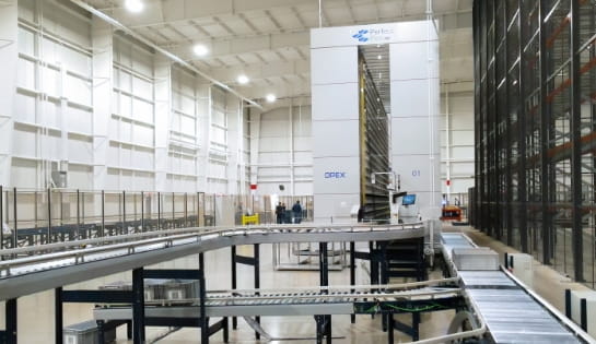 Storage totes traveling on conveyors connected to an OPEX Perfect Pick automated storage system.