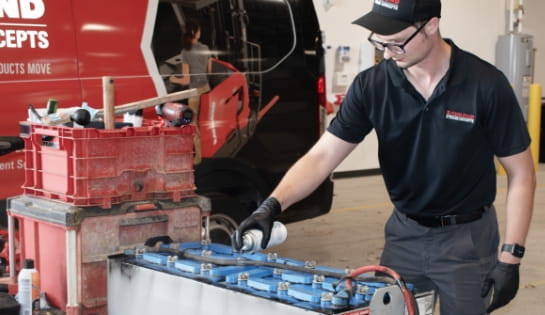 RSC technician performing lead-acid battery maintenance beside a branded service van.