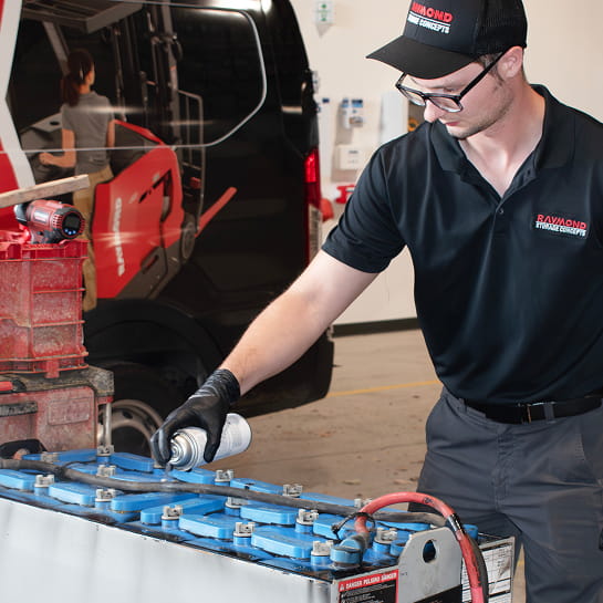 RSC technician performing lead-acid battery maintenance beside a branded service van.