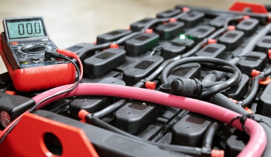 Close-up of an industrial lead-acid forklift battery featuring an integrated diagnostic meter.
