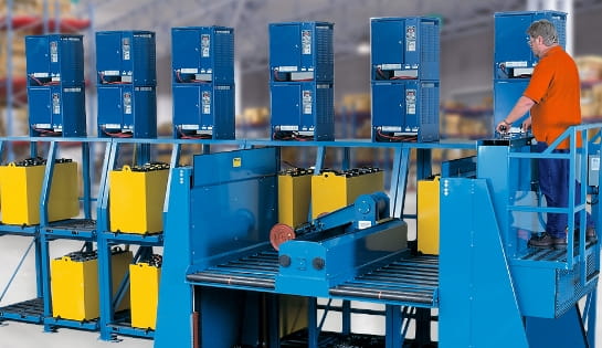 Operator using a semi-automated battery handling system to rack and charge spent forklift batteries.