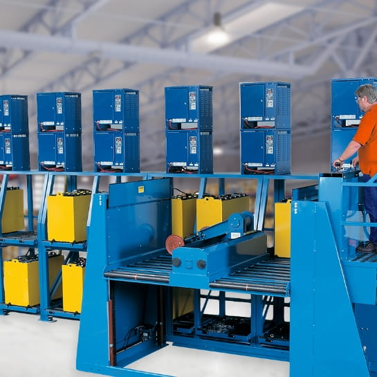 Operator using a semi-automated battery handling system to rack and charge spent forklift batteries.