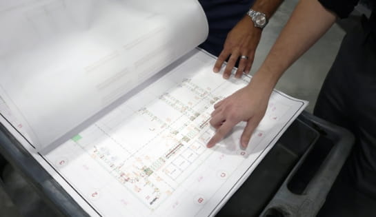 Planning and strategy session reviewing a warehouse floor plan and facility layout.
