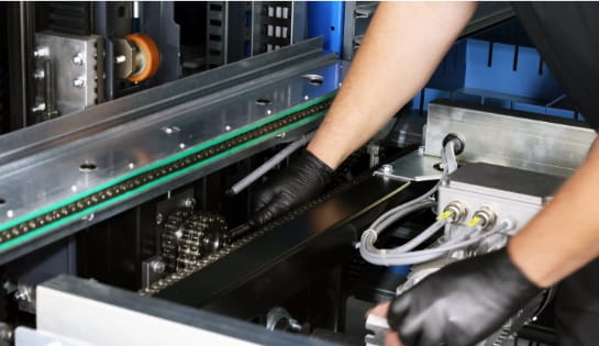 RSC technician inspecting the mechanical drive chains and gears of an AS/RS system.