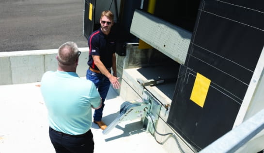 RSC specialist evaluating a warehouse dock leveler alongside a customer in a dock pit.