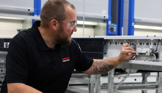 RSC technician inspecting conveyor motor wiring and electrical connections during maintenance.