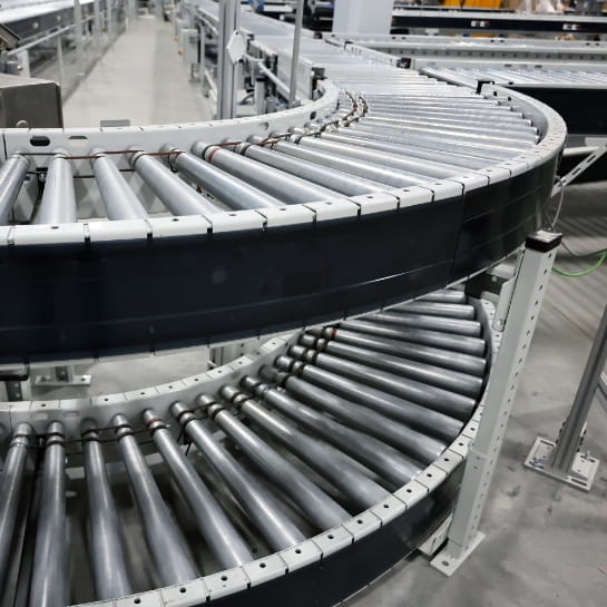 Stacked conveyor belts routing packages around a curve in a warehouse.