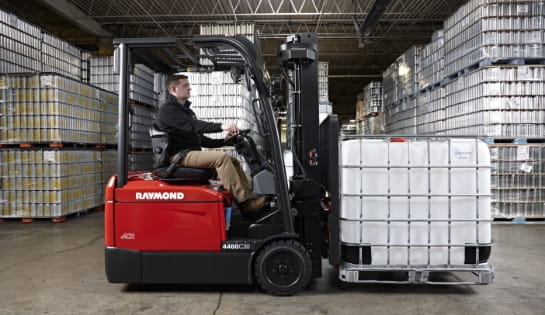 Warehouse operator driving a Raymond counterbalanced forklift carrying a gaylord pallet.