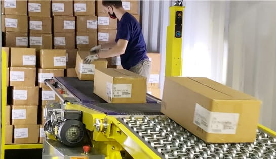Warehouse worker unloading cartons from a trailer onto a Destuff-It portable conveyor system
