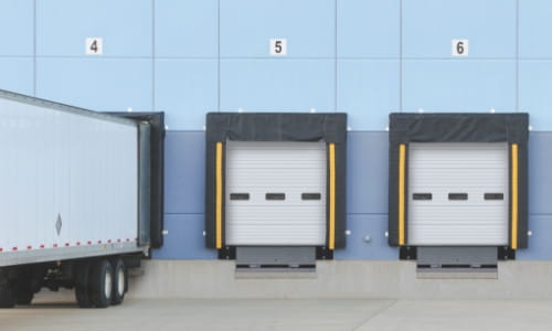Exterior view of a warehouse loading dock with a trailer positioned for material handling.