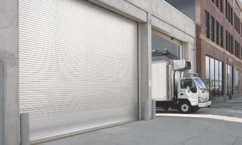 Box truck departing from a warehouse loading dock door.