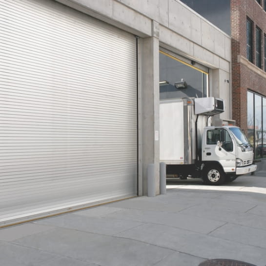 Box truck departing from a warehouse loading dock door.