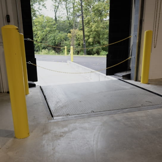 Warehouse receiving area featuring an open loading dock door and dock leveler.