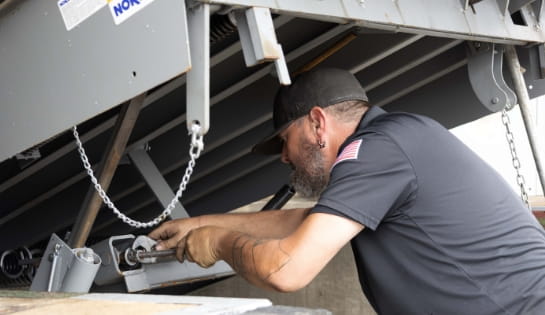 RSC technician using a wrench to perform maintenance on a warehouse dock leveler.