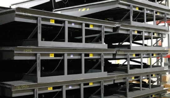 Stacks of new dock levelers stored in a warehouse for installation.