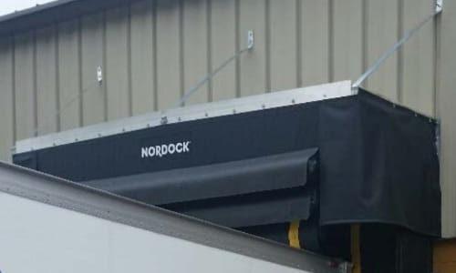 Rain shelter mounted over a semi-trailer at a warehouse loading dock area.