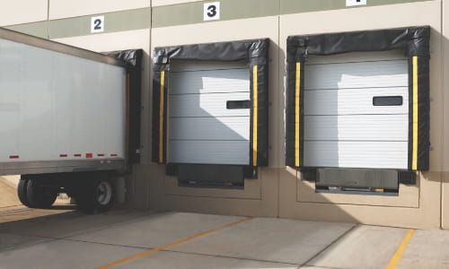 Warehouse loading dock equipped with compression dock seals and a parked trailer.