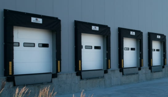 Exterior view of a warehouse loading dock facility with multiple dock doors and shelters.