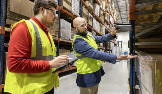 Operations manager measuring vertical storage space while a Raymond Storage Concepts engineer takes notes