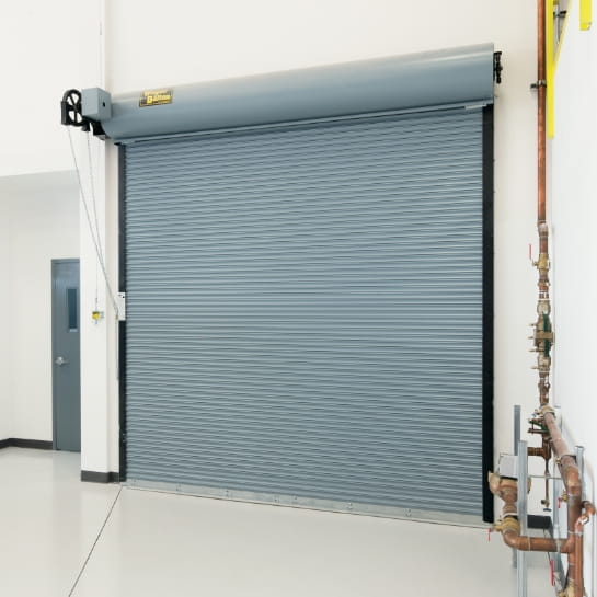 Gray fire-rated steel rolling door installed inside a warehouse building.
