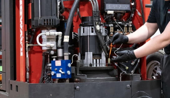 Close-up of a technician checking the oil in a Raymond forklift engine