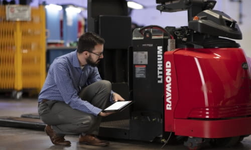Raymond Storage Concepts professional using a tablet to inspect a Raymond forklift