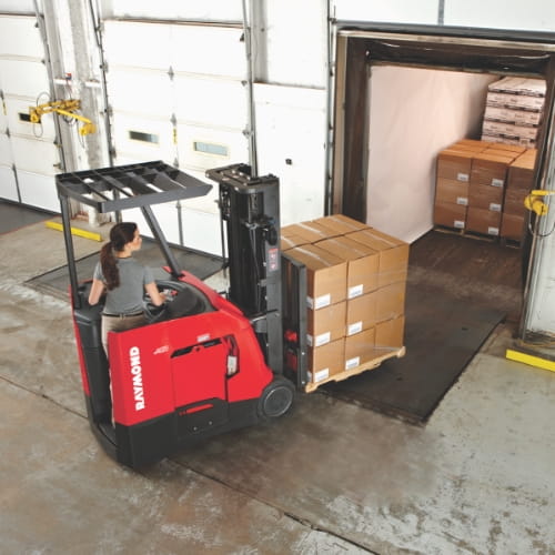 Raymond counterbalanced forklift and operator loading a pallet into a semi-truck at a warehouse dock