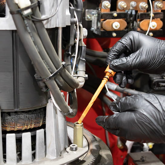 Gloved technician hand checking oil stick in a Raymond forklift engine.