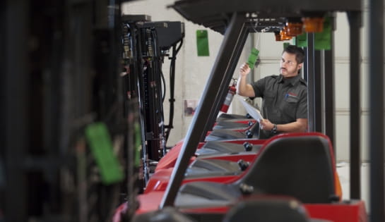 Raymond Storage Concepts employee checking a green inspection tag on a forklift