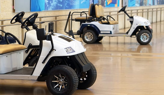 Two parked white utility golf carts in an indoor facility hallway