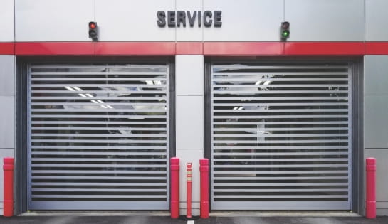 Steel high-speed doors installed in the service entrance of a commercial car dealership
