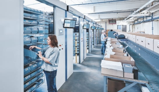 Worker picking a product from a bin housed in a Kardex horizontal carousel system