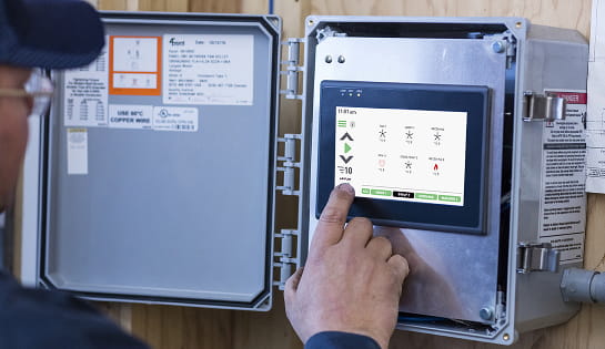 Person adjusting settings on an industrial fan control panel