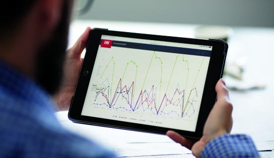 Man reviewing fleet data and analytics on a tablet displaying the iWAREHOUSE dashboard reports