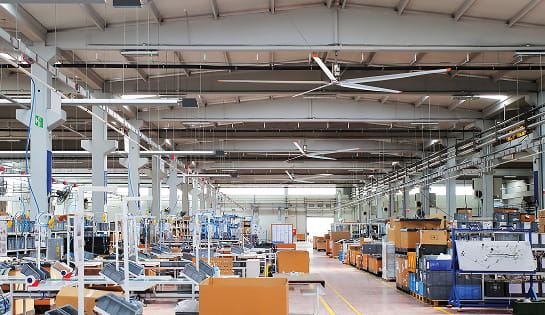 Industrial ceiling fan installed overhead in a busy manufacturing floor