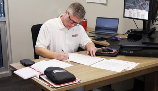 Raymond Storage Concepts employee reviewing paperwork at his desk surrounded by computers, monitors and notebooks in our Cincinnati branch office