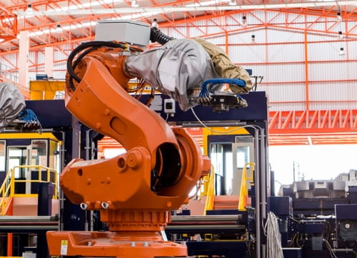 Orange robotic arm operating in an outdoor construction area