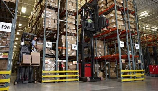 Two orderpickers with operators pulling boxes off racking shelves in a warehouse