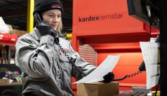 Raymond Storage Concepts parts specialist taking a phone order in the parts cage with a Kardex Remstar AS/RS in the background