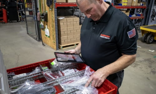 Raymond Storage Concepts parts specialist holding a tablet while counting inventory for a consignment customer in a warehouse facility