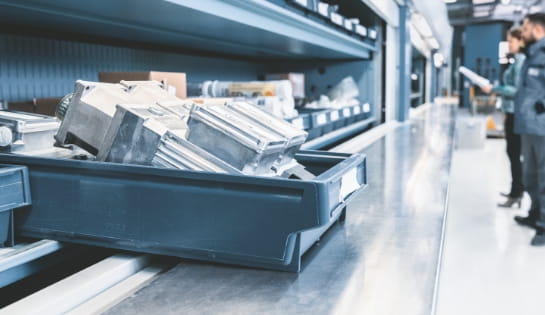 Tote filled with conveyor replacement parts sitting on a metal storage shelf in a warehouse facility