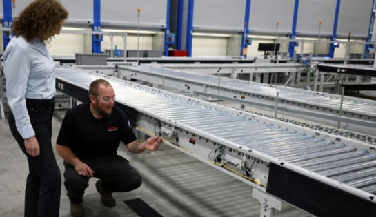 Raymond Storage Concepts technician showing a customer a conveyor motor in a warehouse receiving line
