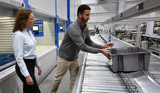 Raymond Storage Concepts automation specialist demonstrating a tote picking automation system to a customer in a warehouse facility