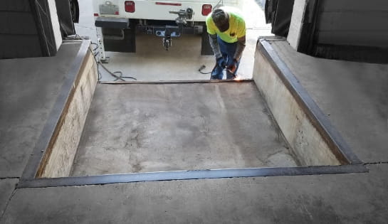 Warehouse dock pit featuring a pit-mounted dock leveler ready for freight loading operations