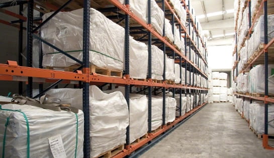 Rack aisle featuring push back racking systems holding pallets of wrapped cartons in a warehouse facility