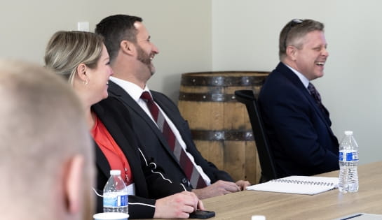 Three Raymond Storage Concepts employees in professional attire collaborating and laughing in a conference room