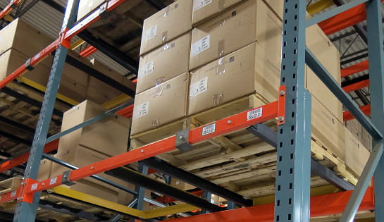 Pallet of cartons securely positioned on an upper level of an industrial pallet racking system